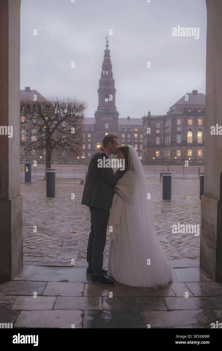 Couple de mariage romantique embrassant sous arche le jour de pluie Banque D'Images