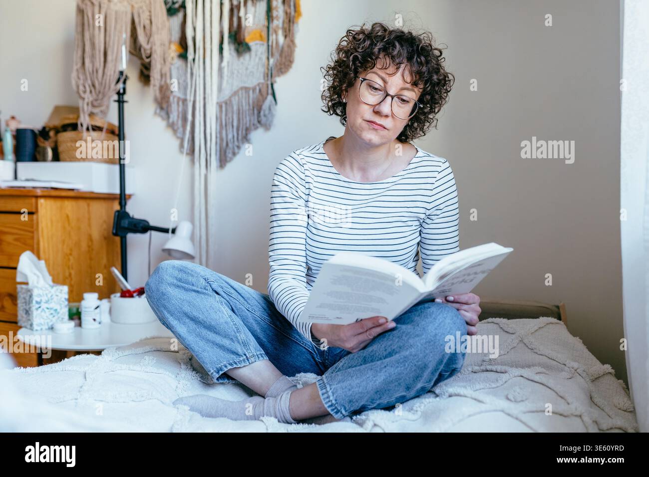 Jolie femme confiante dans son livre de lecture des années 40 sur le lit à la maison Banque D'Images