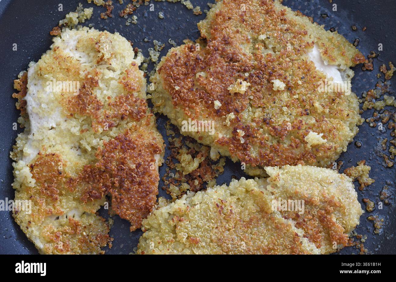 Filets de poulet en croûte de quinoa disposés sur une assiette, vue de dessus, présentant une texture croustillante dorée et des ingrédients sains. Idéal pour les concepts de santé Banque D'Images