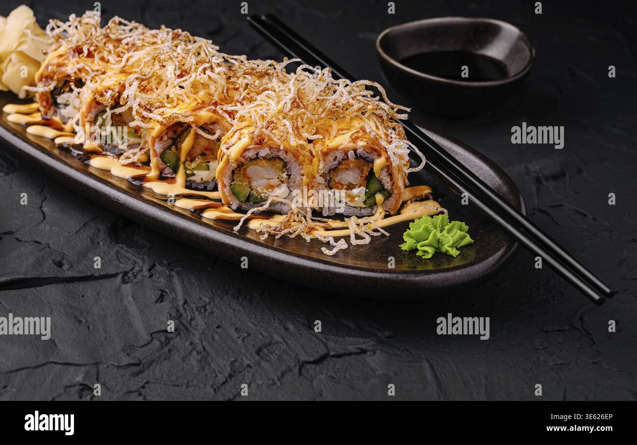 Nourriture, délicieux rouleaux de sushi sont astucieusement disposés sur une assiette sombre. Les rouleaux sont recouverts d'une couche croustillante, arrosés de sauce, et accompagnés de W. Banque D'Images