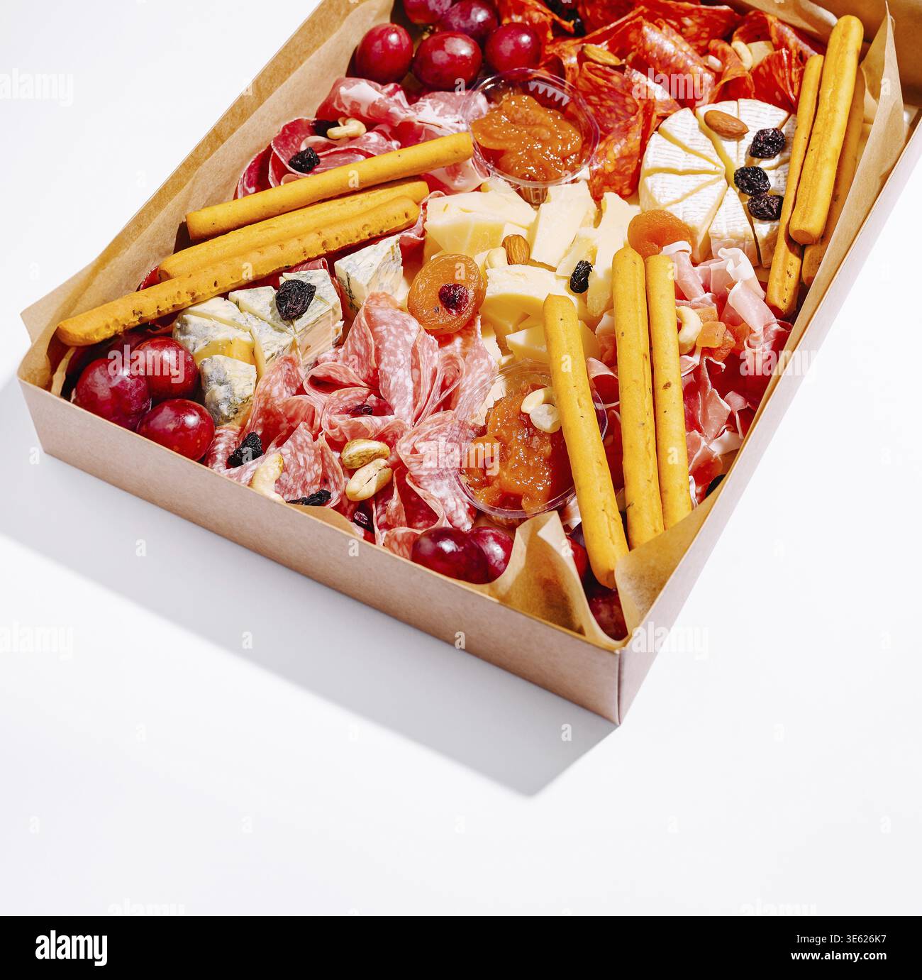 Nourriture, Un tableau de charcuterie magnifiquement arrangé présente une variété de charcuteries, fromages assortis, raisins, fruits secs et gressins, parfait fo Banque D'Images