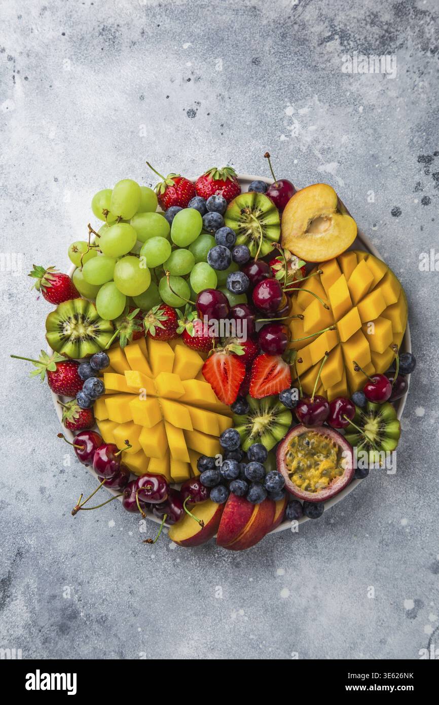 Nourriture, délicieux fruits et plateau de baies. Mangue, kiwi, fraise, raisin, cerise, myrtille, pêche et fruit de la passion, vue de dessus Banque D'Images