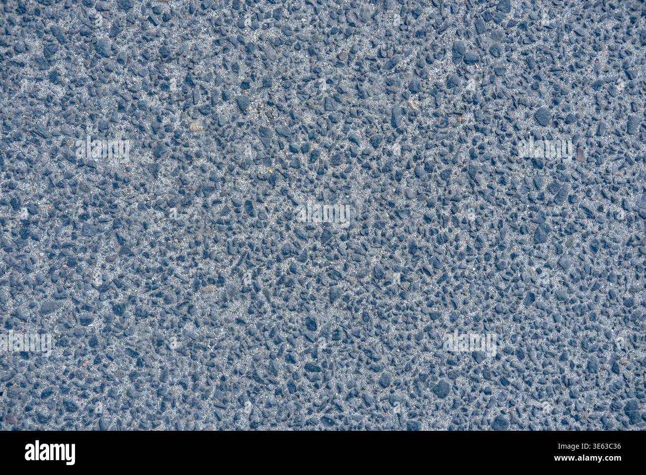 La surface d'asphalte gris avec des pierres d'agrégat visibles est montrée comme un fond de texture de route Banque D'Images