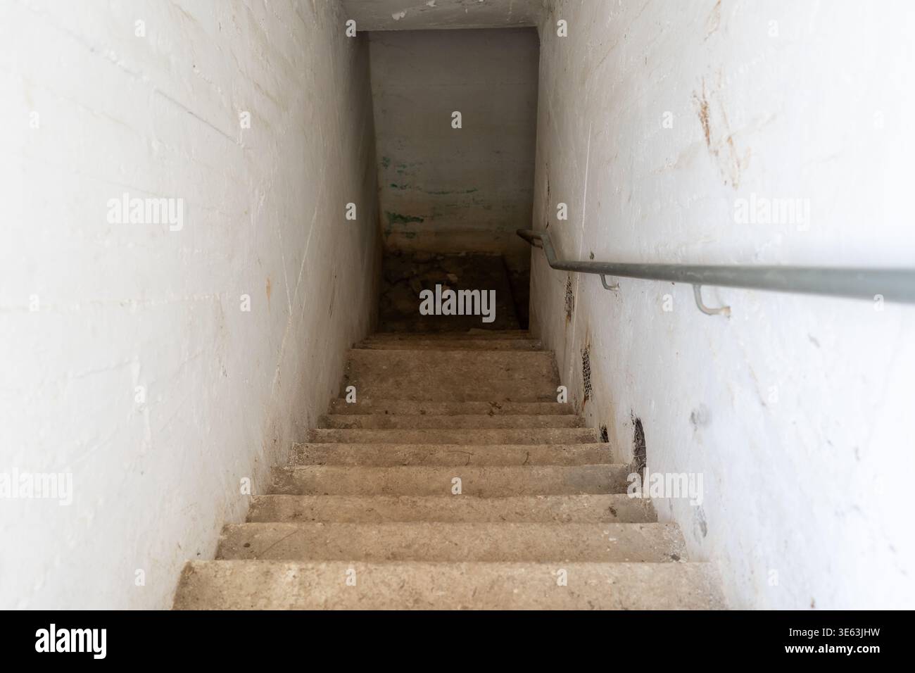 Une vue en bas des escaliers menant à un abri de bombe en béton en Israël. L'abri présente des murs simples et un escalier simple. L'environnement est clos et utilitaire dans son but. Banque D'Images