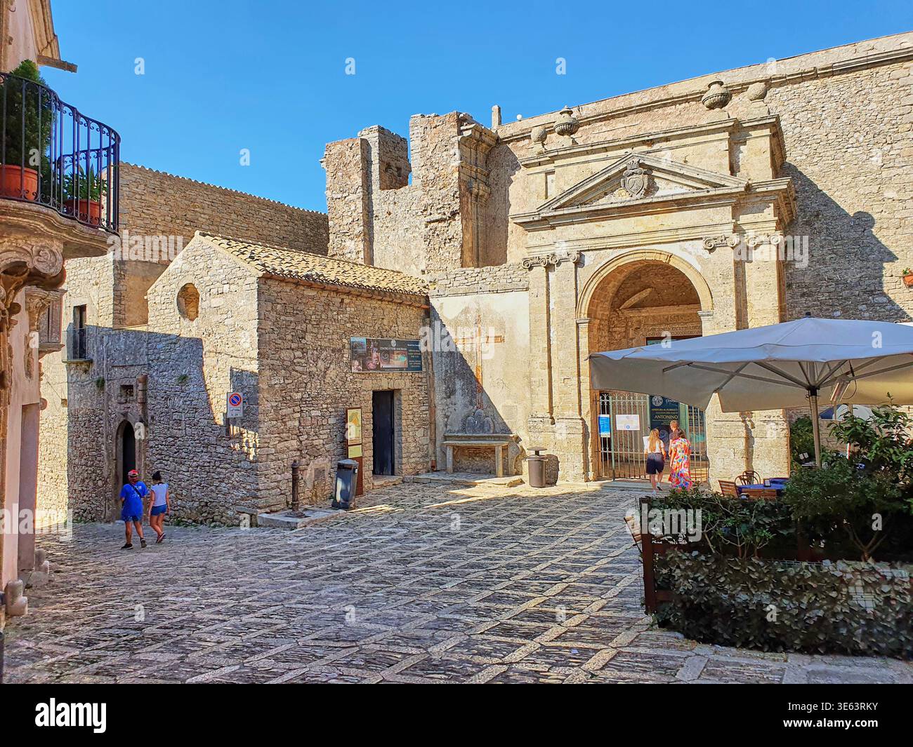 Une place pavée ensoleillée dans la ville historique de colline d'Erice, Sicile, Italie, avec le grand portail voûté de la Chiesa Madre (église mère) Banque D'Images