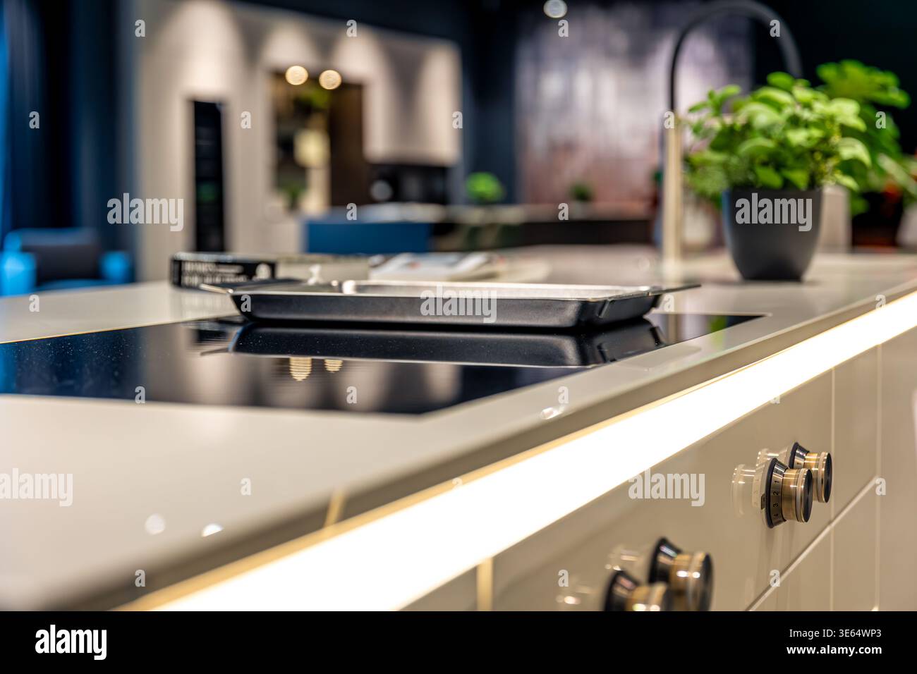 Table de cuisson à induction moderne sur comptoir blanc. Design de cuisine élégant avec éclairage. Banque D'Images