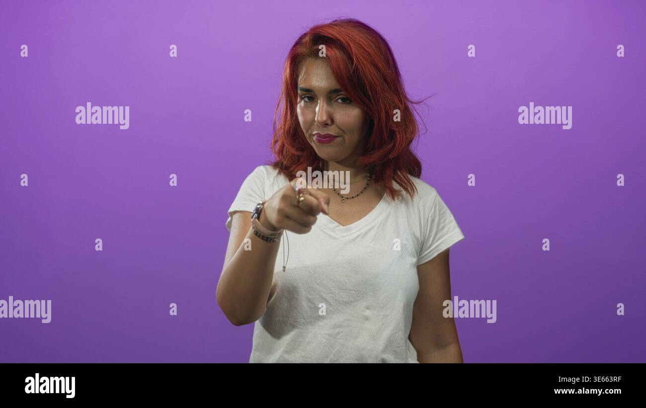 Femme avec le doigt à la tempe et le geste du doigt pointant dans le studio violet ; assurance de la mise au point de l'assertivité. Banque D'Images