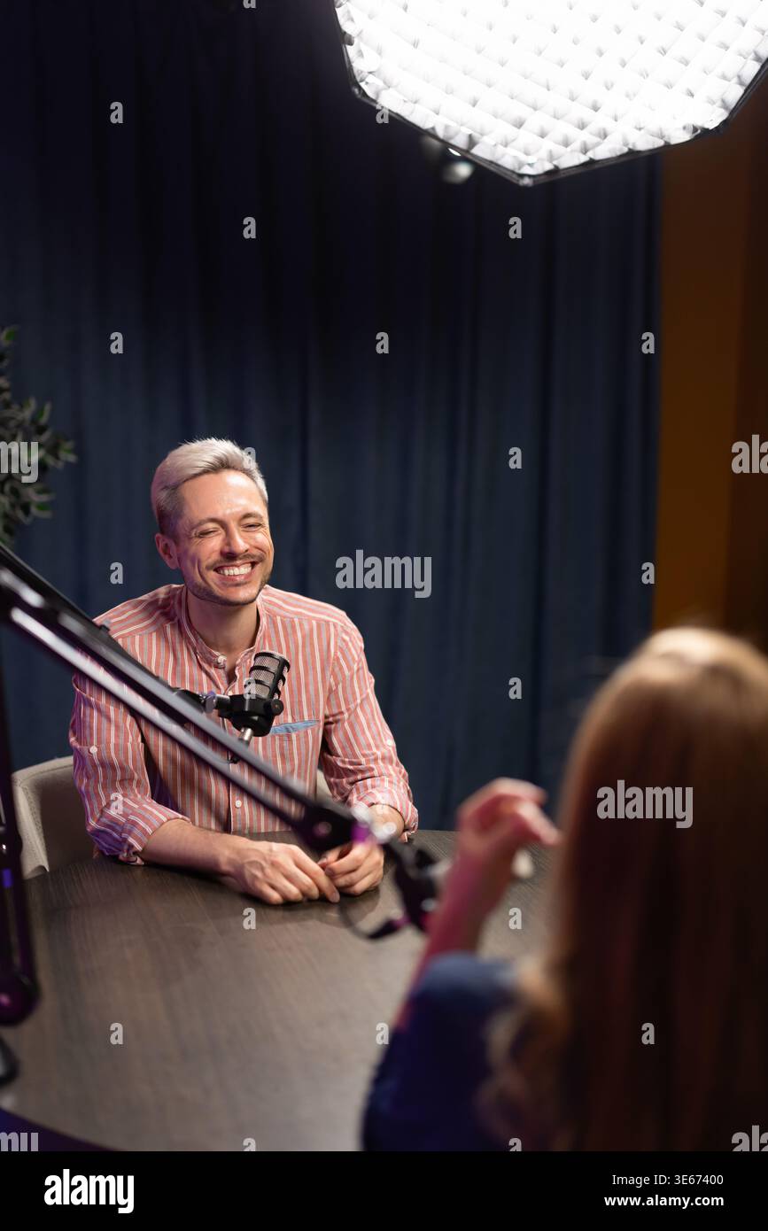 Annonceur masculin souriant enregistrant un podcast audio pendant une session de diffusion en direct Banque D'Images