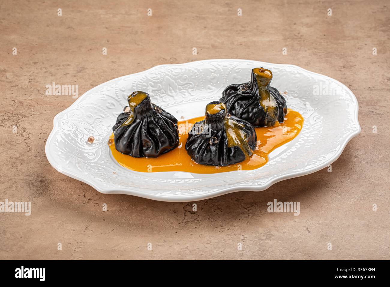 Boulettes khinkali noires avec sauce sur assiette Banque D'Images