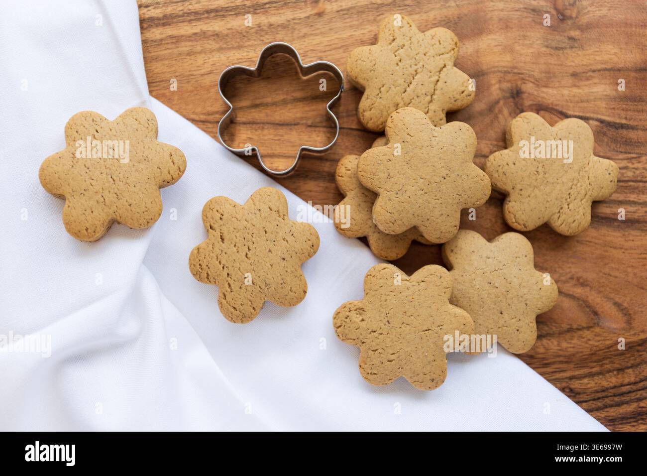 Gros plan de biscuits dorés faits maison disposés sur une surface en bois. Les tons chauds et la lumière naturelle créent une atmosphère chaleureuse de cuisson. Banque D'Images