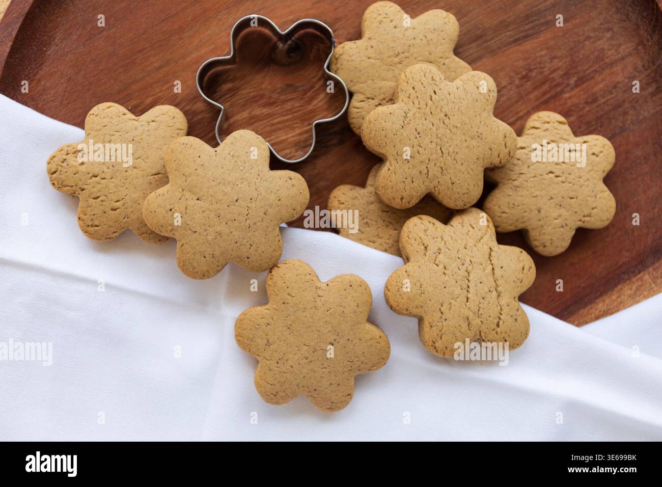 Gros plan de biscuits dorés faits maison disposés sur une surface en bois. Les tons chauds et la lumière naturelle créent une atmosphère chaleureuse de cuisson Banque D'Images