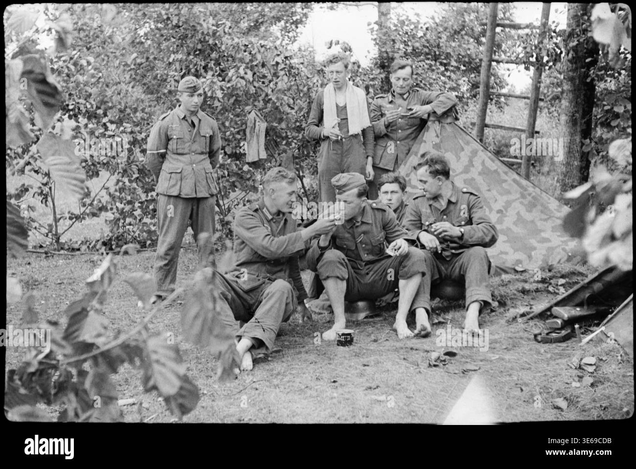 Soldats de la Wehrmacht reposant près de Zeltbahn abris à l'extérieur, photographie 24×36 mm***positive à partir d'un négatif film 24×36 mm. Showin photo noir et blanc Banque D'Images