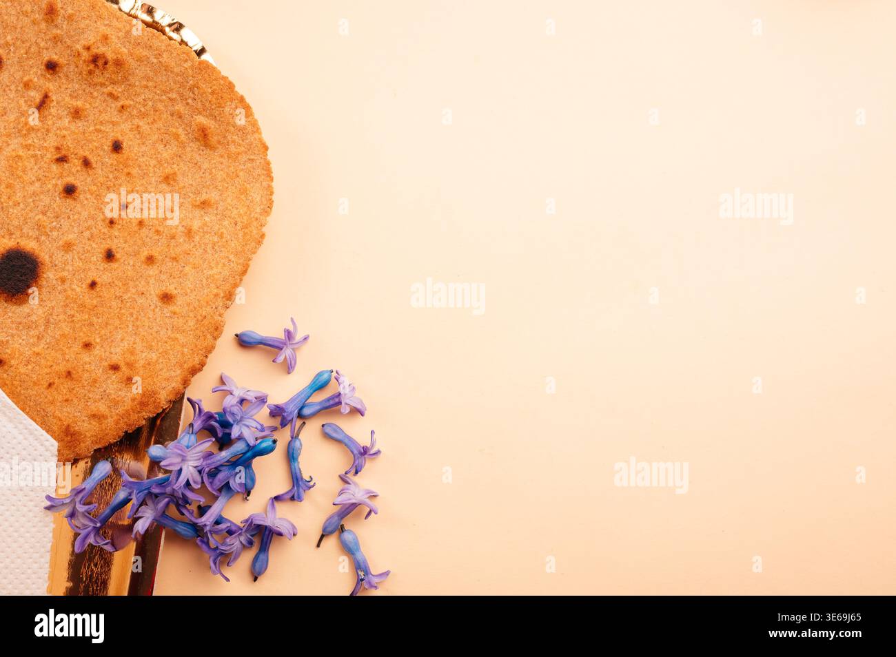 Matzah et pétales. Tons chauds soulignant l'ambiance festive avec ombres et lumière naturelle Banque D'Images