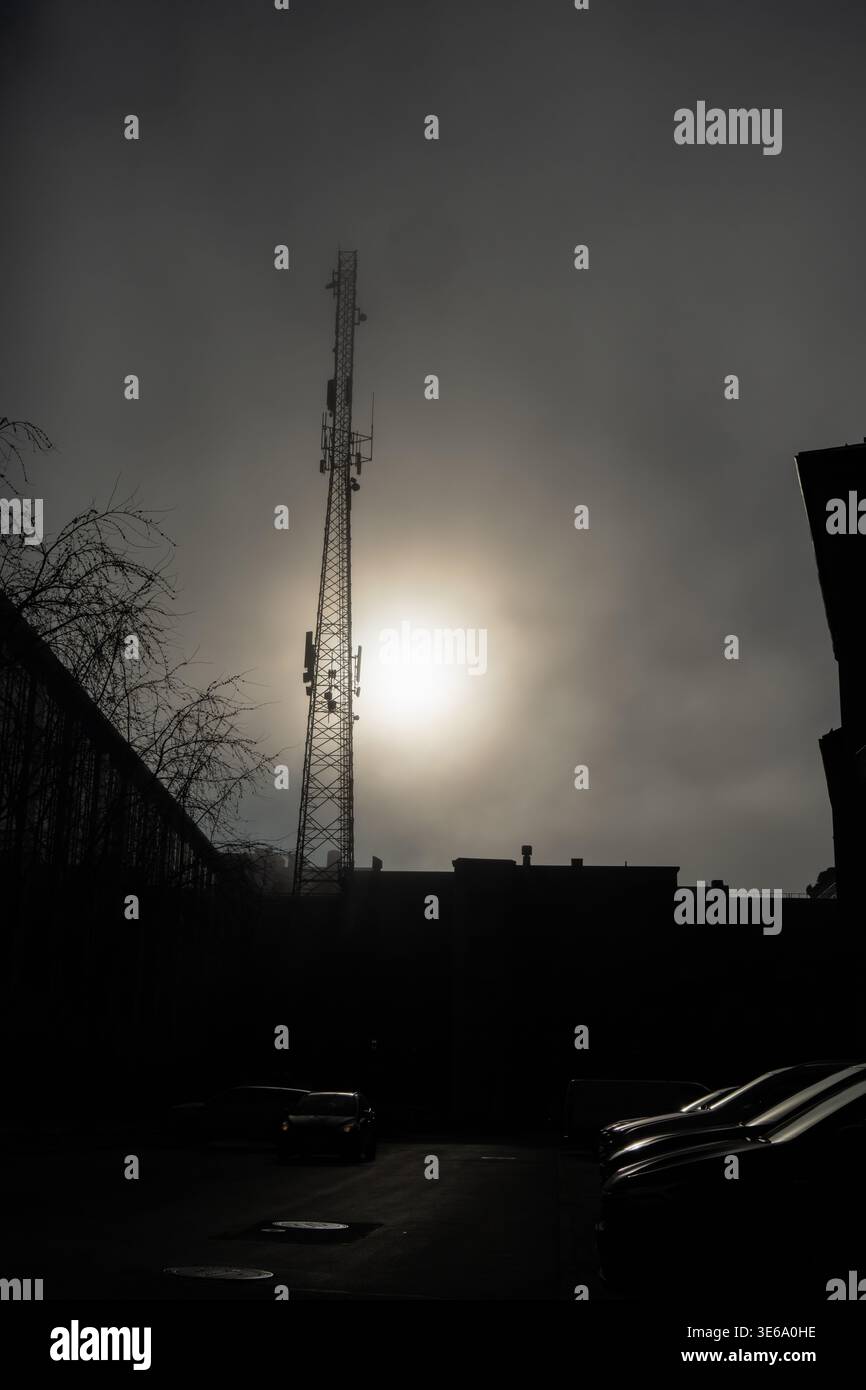 Tour en treillis métallique industrielle pour signaux de téléphonie mobile debout dans un brouillard dense avec un halo de soleil brillant fournissant un regard conceptuel sur la connectivité globale Banque D'Images