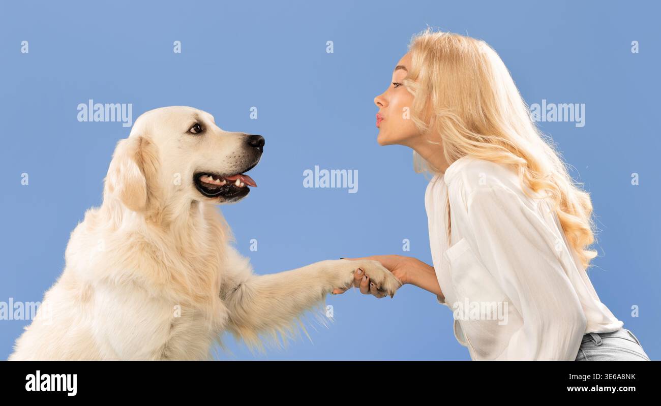 Femme et chien partagent un moment avec un fond bleu et une interaction ludique Banque D'Images