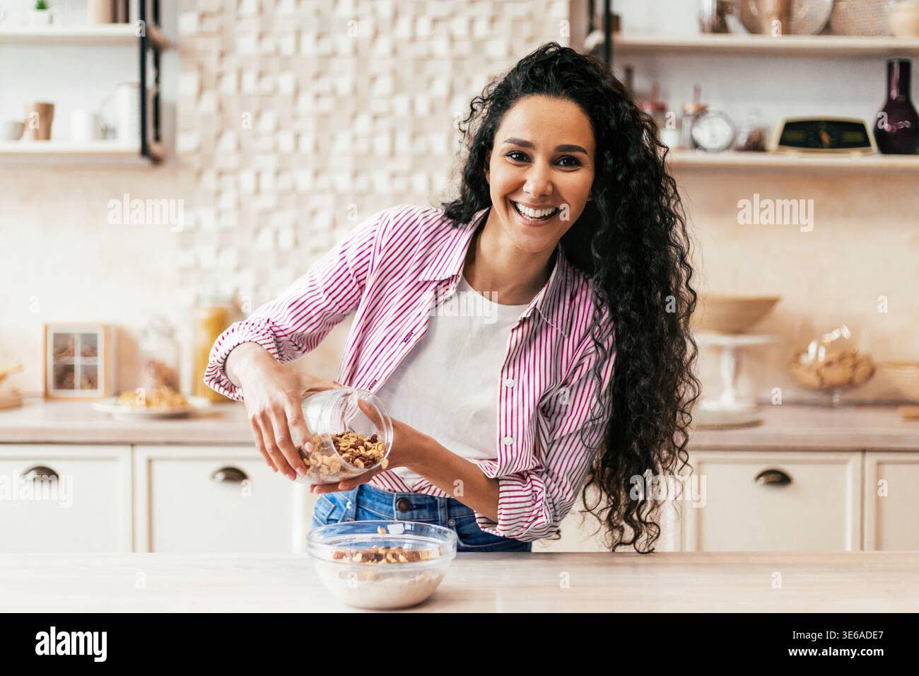 Femme prépare une collation saine dans une cuisine moderne tout en souriant joyeusement Banque D'Images