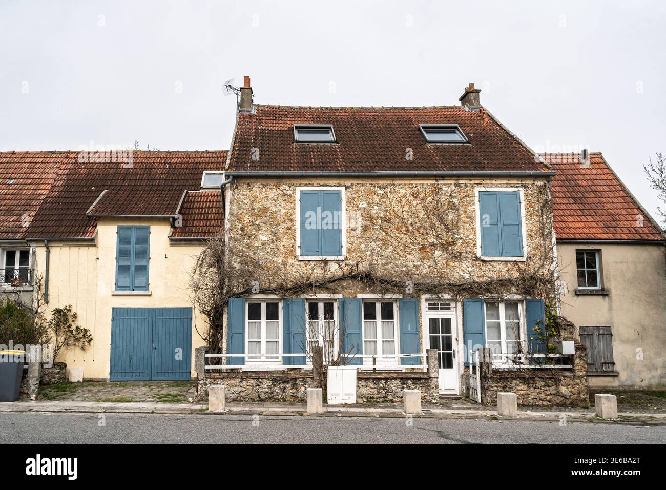 Vue de face d'une ancienne maison d'habitation française dans un village, montrant des murs de pierre, des volets bleus et un toit carrelé, illustrant un logement traditionnel, rural Banque D'Images