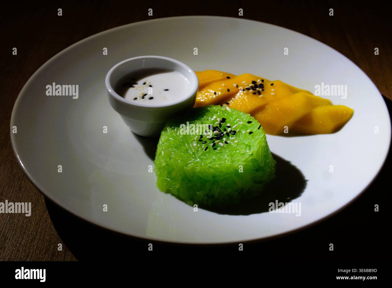 Gros plan du riz collant thaïlandais classique à la manggo, un dessert thaïlandais populaire servi avec du riz collant à la noix de coco sucré, une tranche de manggo fraîche et mûre, des graines de sésame noir. Banque D'Images