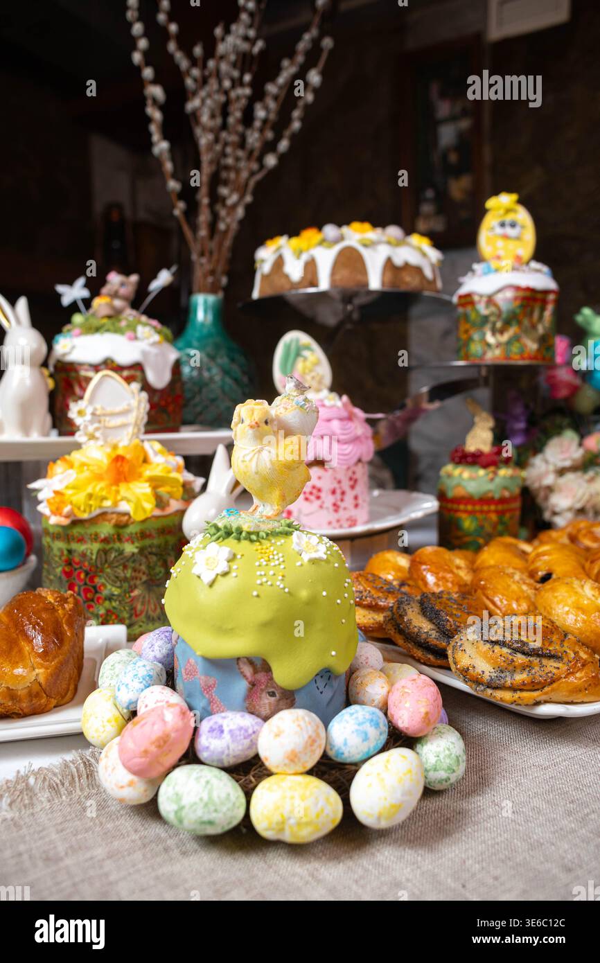 Table de Pâques : Kulichi en moules peints, œufs décorés, pâtisseries et poussins figurines Banque D'Images