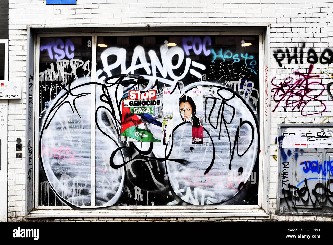 un mur de briques blanches à Paris, France, couvert d'art de rue, de tags de peinture en aérosol noir et blanc et d'affiches collées - Paris - France Banque D'Images