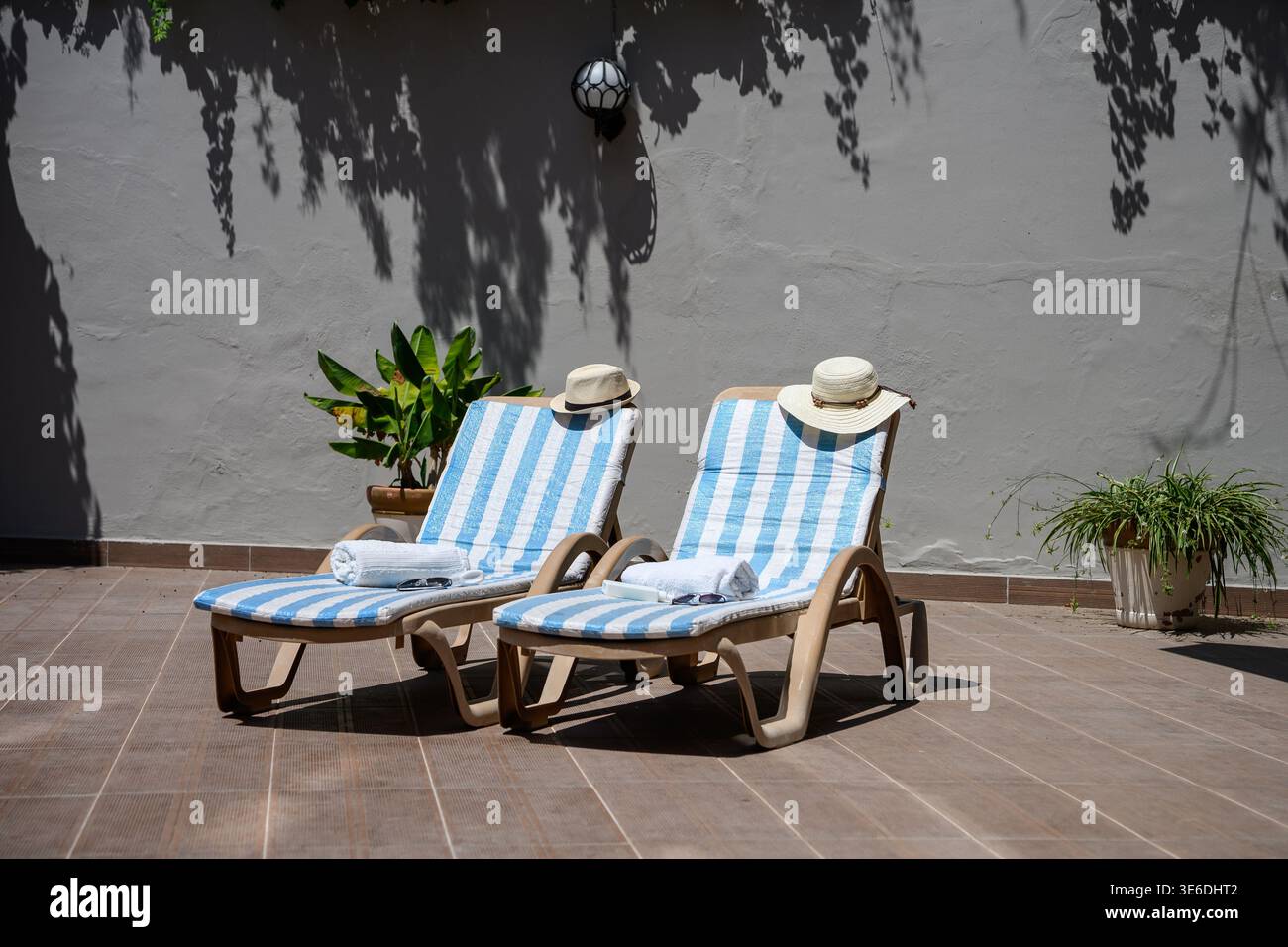 Deux chaises longues vides avec chapeaux de paille et serviettes sur une terrasse ensoleillée. Vacances d'été, détente et concept de luxe Resort, voyage. Outdoo minimaliste Banque D'Images