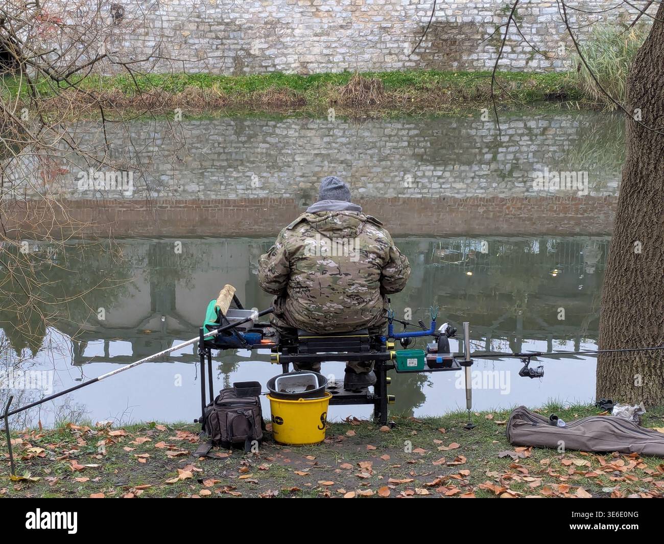 Fisherman est assis sur la rive dans le centre-ville, Młynówka. Opole, Pologne. - Image de stock capturée avec un smartphone