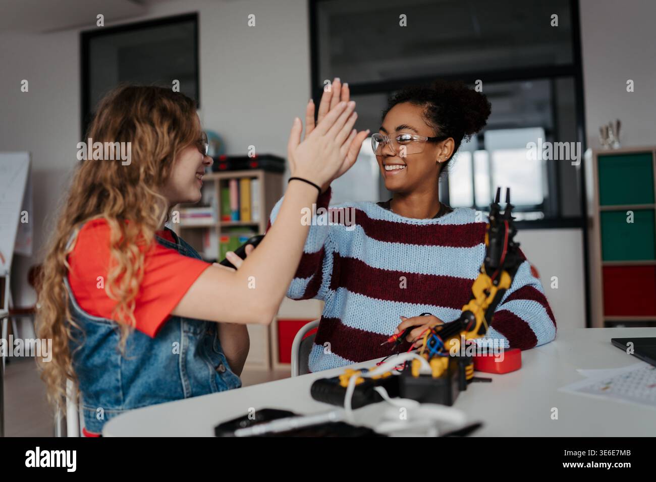 Des lycéens travaillant sur un projet de robotique, en utilisant l'application d'IA en ligne pour répondre aux questions. Banque D'Images