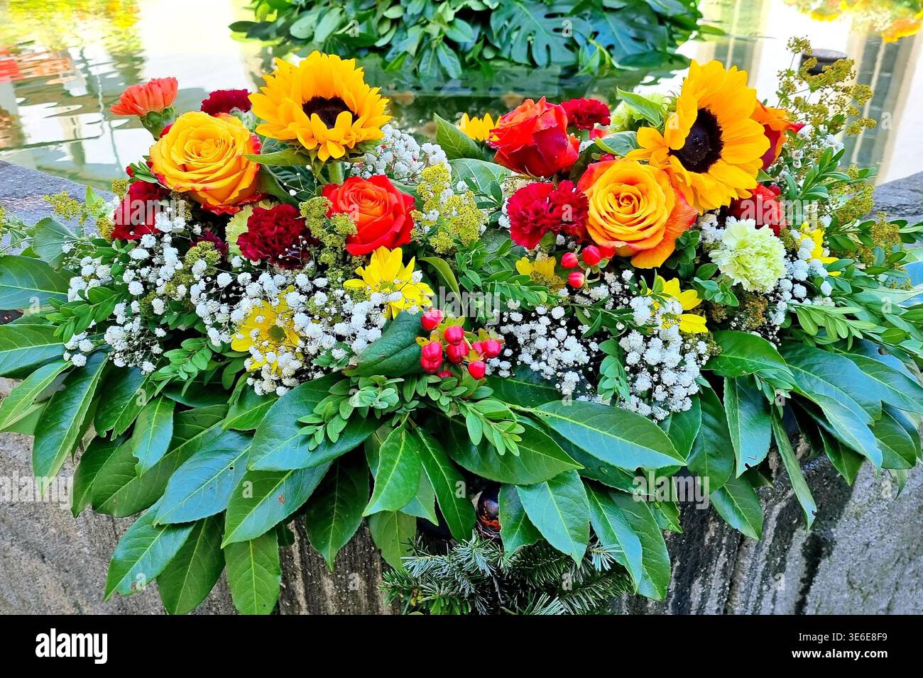 Un arrangement floral vibrant décore la bordure en pierre d'une fontaine. Banque D'Images