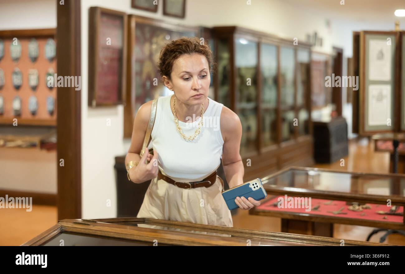 Femme examinant des artefacts antiques dans la vitrine en verre dans le musée Banque D'Images