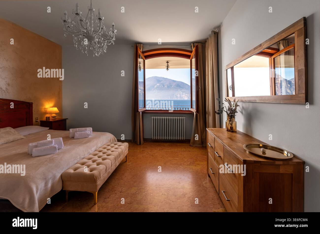 Élégante villa de luxe dans une retraite italienne au bord du lac, avec lustre, mobilier en bois chaleureux et fenêtre ouverte encadrant le lac serein et mountai Banque D'Images