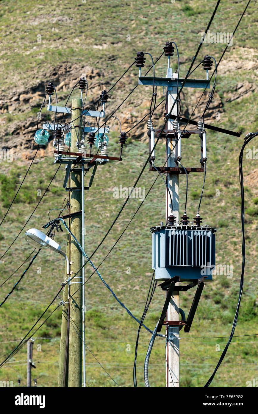 Lignes électriques et transformateur sur des poteaux de distribution surplombant un paysage de colline rurale Banque D'Images