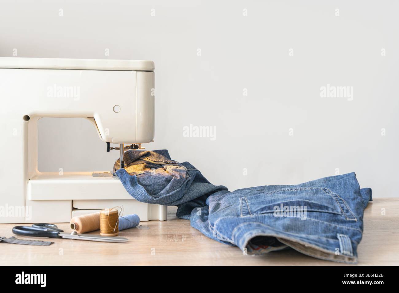 Machine à coudre travaillant sur le denim lourd, préparant un vêtement. Artisanat et confection de passe-temps à l'atelier à la maison Banque D'Images