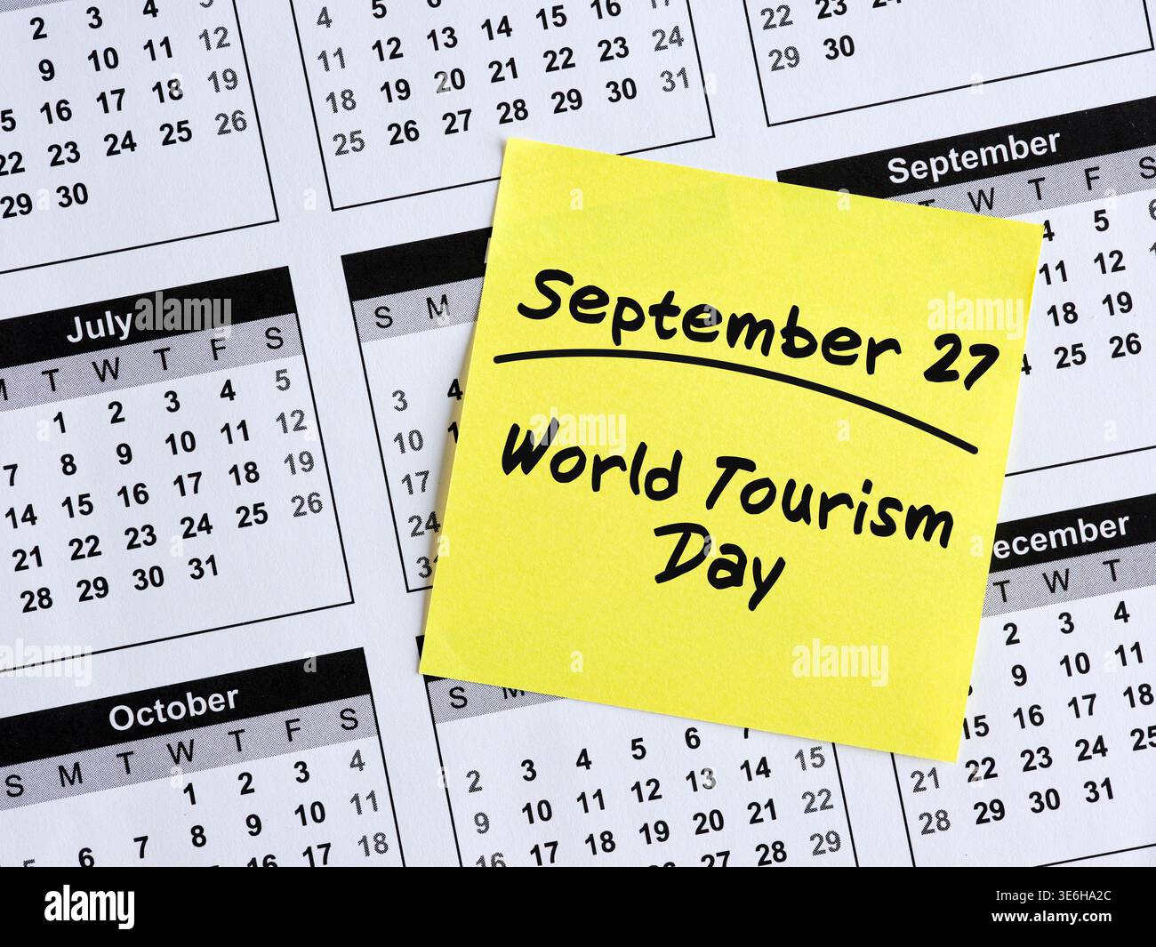 Note autocollante jaune avec texte manuscrit septembre 27, journée mondiale du tourisme reposant sur la page du calendrier Banque D'Images