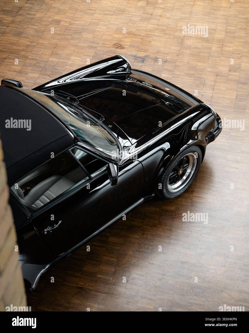 Porsche 911 cabriolet classique noir sur parquet. Vue de haut en bas d'une partie avant droite d'une Porsche 911 cabriolet des années 1980 avec capote souple. Banque D'Images