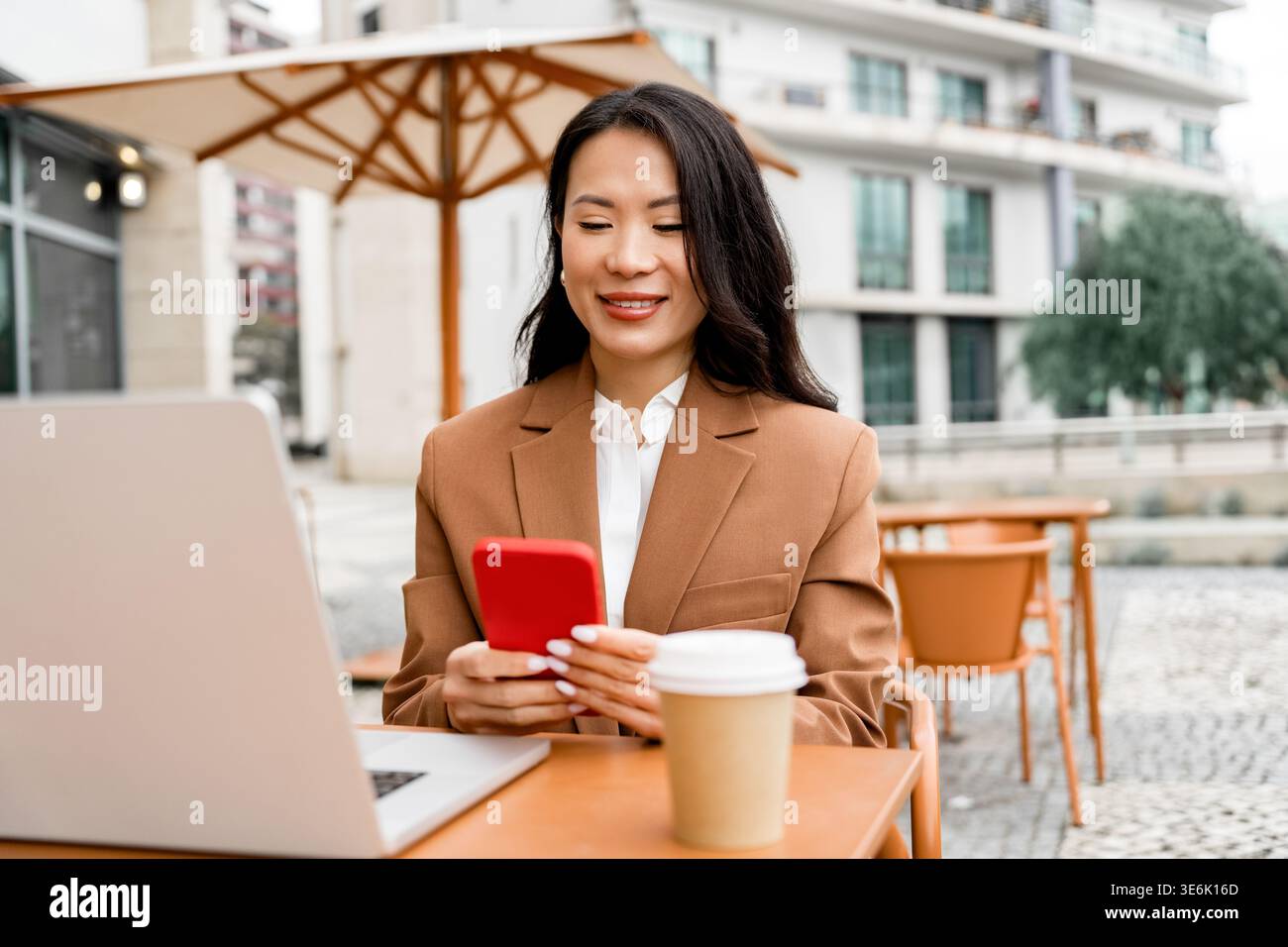 Femme d'affaires utilisant smartphone avec ordinateur portable au café extérieur Banque D'Images