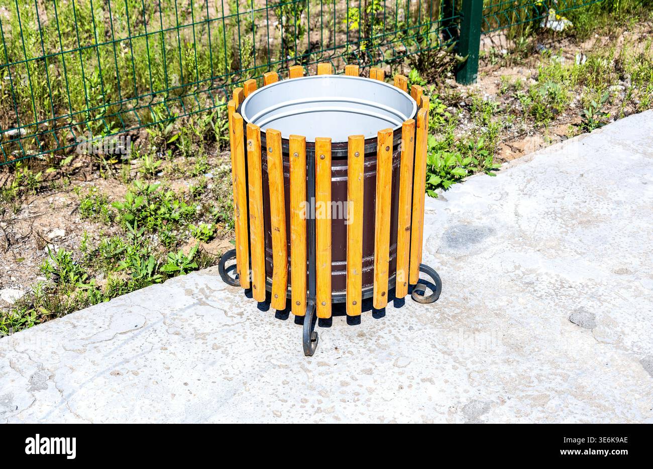 Une poubelle robuste en métal et en bois est placée bien en vue, servant de conteneur à déchets pour éliminer efficacement divers articles et maintenir propre Banque D'Images