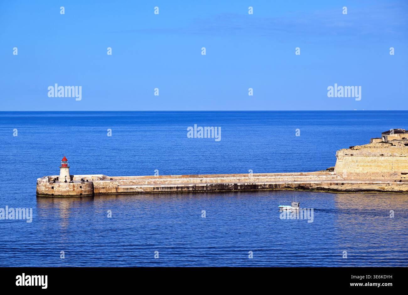 Une vue panoramique sur le phare de Ricasoli situé au bout du brise-lames Grand Harbour East à Kalkara, près de la Valette, Malte. Un petit bo de pêche Banque D'Images