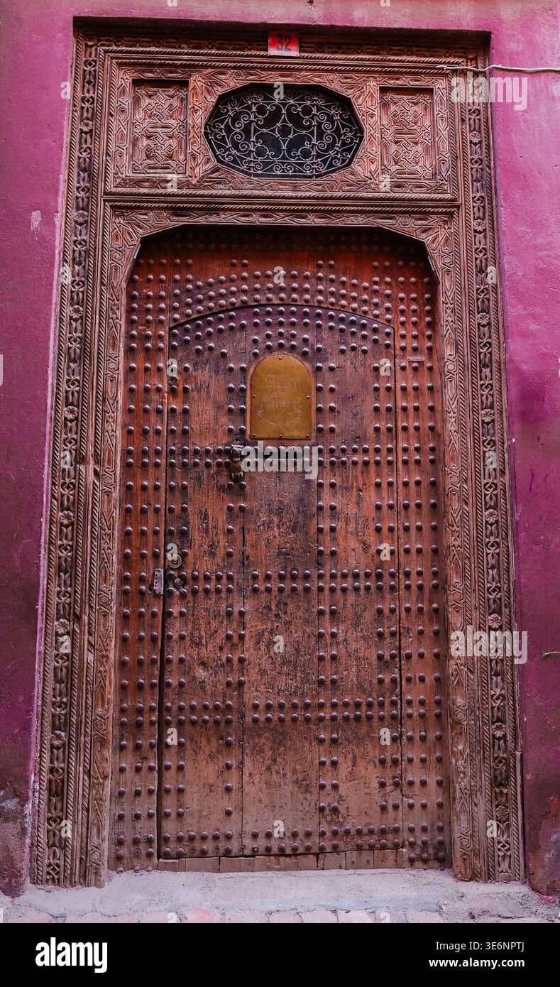 Porte en bois cloutée finement sculptée dans la médina de Marrakech, Maroc Banque D'Images