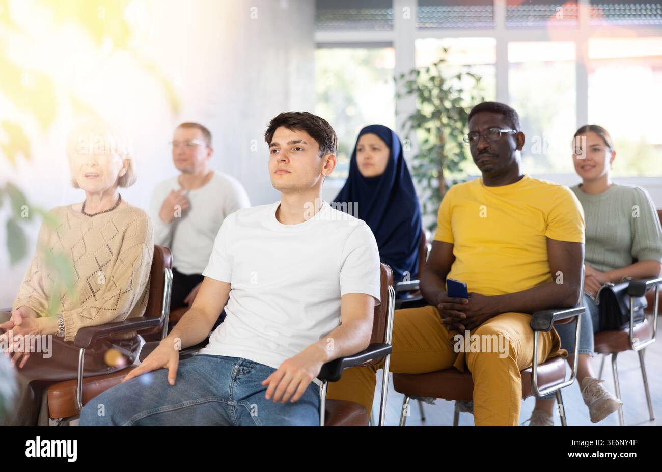 Guy Teenager écoute la conférence tout en étant assis sur la chaise Banque D'Images