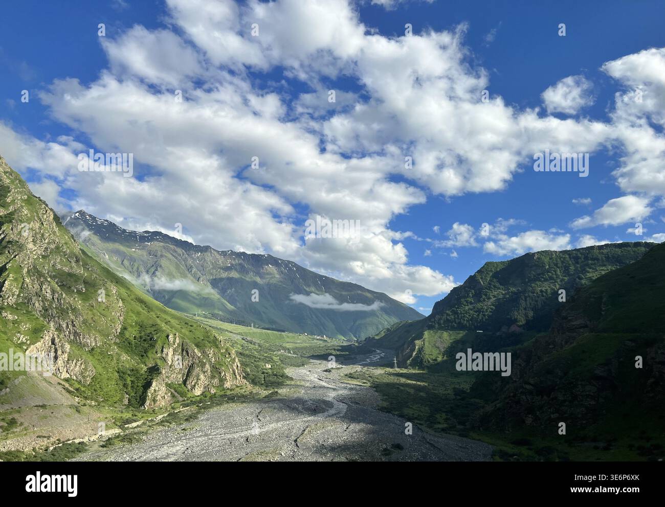 Large vallée de montagne avec rivière, route et pentes vertes dans le Grand Caucase, région de Kazbegi, Mtskheta-Mtianeti, Géorgie. - Image de stock capturée avec un smartphone