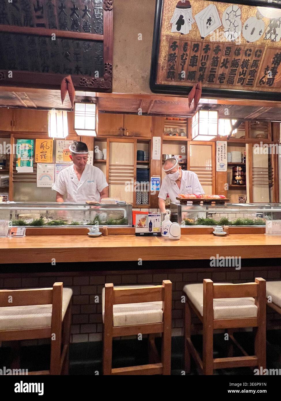 Deux chefs sushis travaillant derrière le comptoir dans un restaurant de sushis traditionnel à Tokyo, au Japon. Banque D'Images