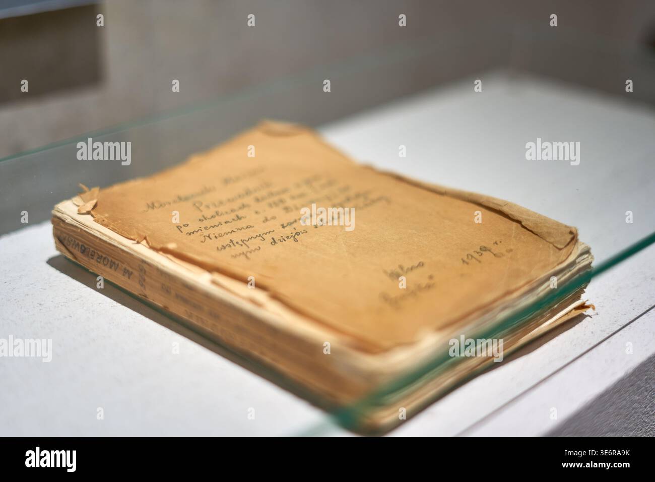 Un manuscrit ou document manuscrit vieilli et jauni, exposé sous une vitre de protection sur une surface blanche. Le papier usé présente des signes importants Banque D'Images