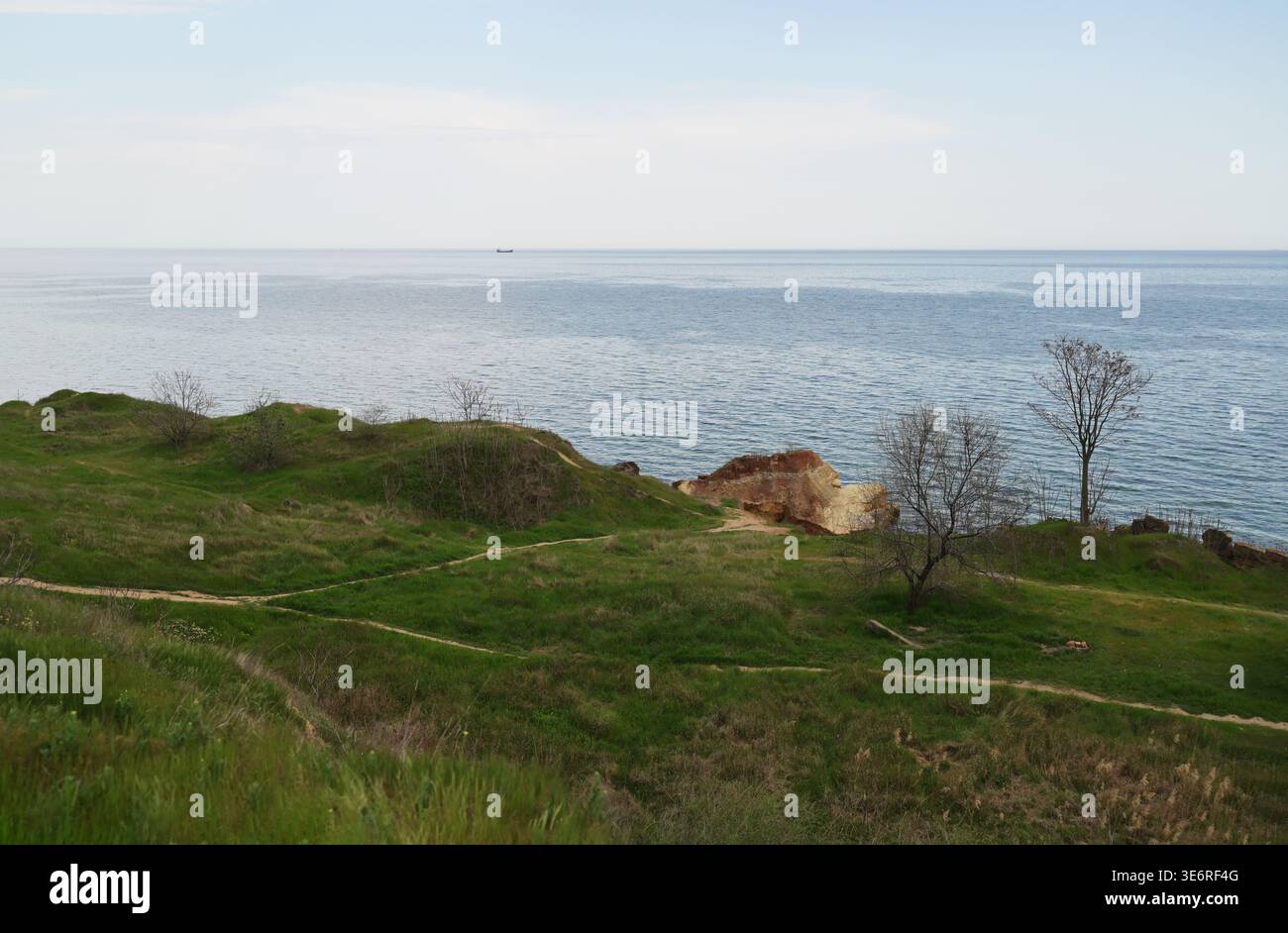 Collines verdoyantes avec des affleurements rocheux surplombant la mer bleue sous un ciel doux. Concept de beauté côtière accidentée, paysage naturel géologique, et printemps s. Banque D'Images
