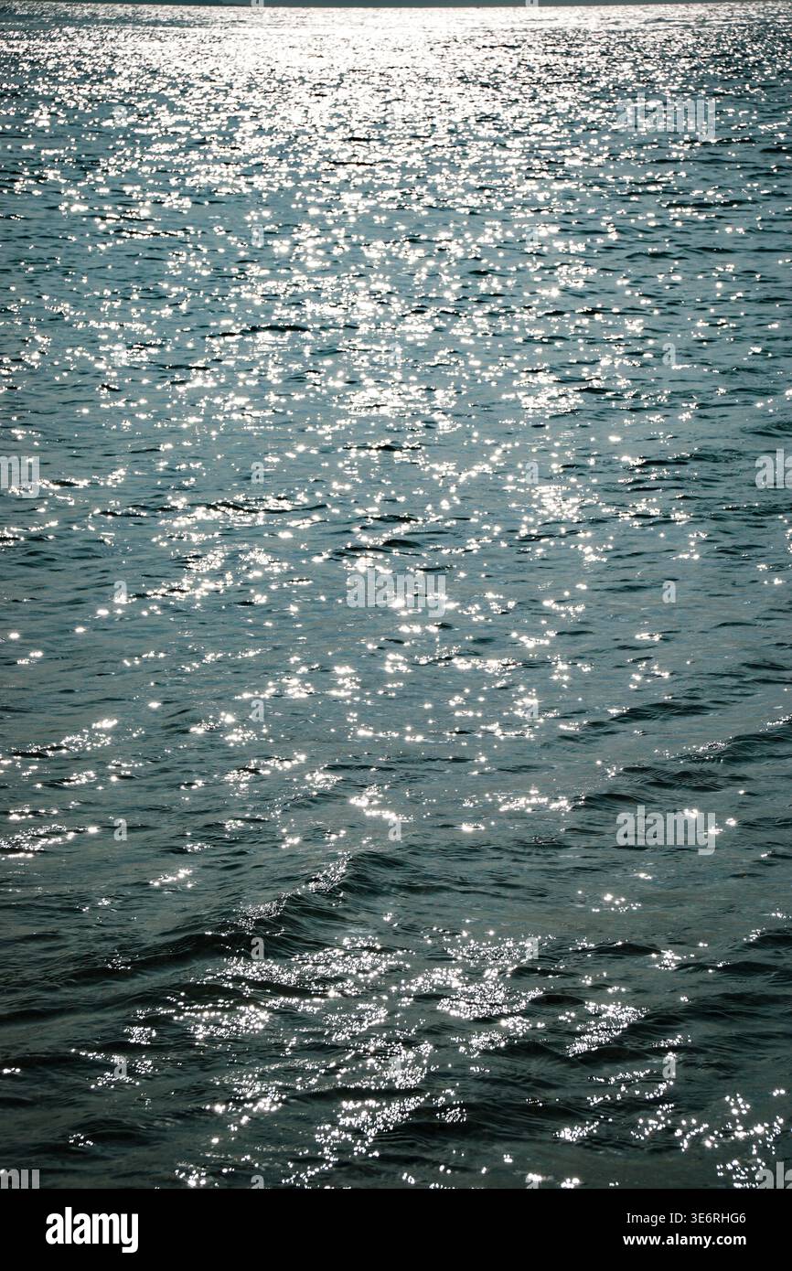 La lumière du soleil se reflétant sur la surface ondulante de l'eau créant des reflets lumineux à travers la mer ouverte ou le lac pendant la journée Banque D'Images