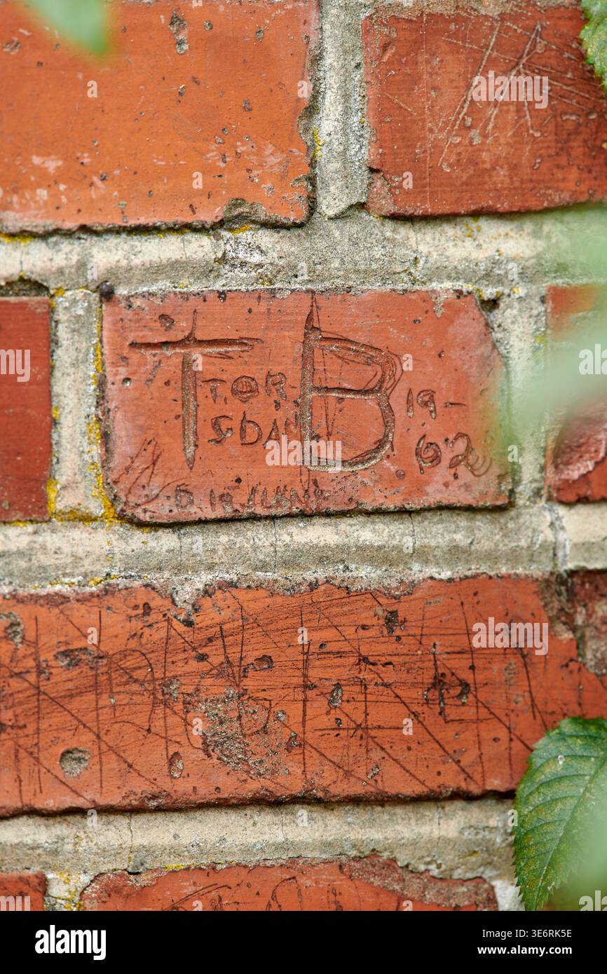 Mur de briques, lettre et pierre avec écriture sur la structure de bâtiment en béton pour la mémoire ou l'empreinte. Vide, vandalisme et graffiti avec blocs rectangulaires Banque D'Images