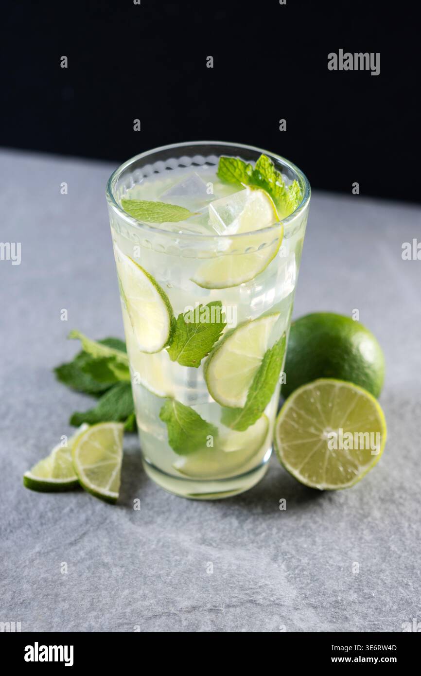 Cocktail de mojito frais avec citron vert, menthe et glace dans le verre sur fond sombre Banque D'Images