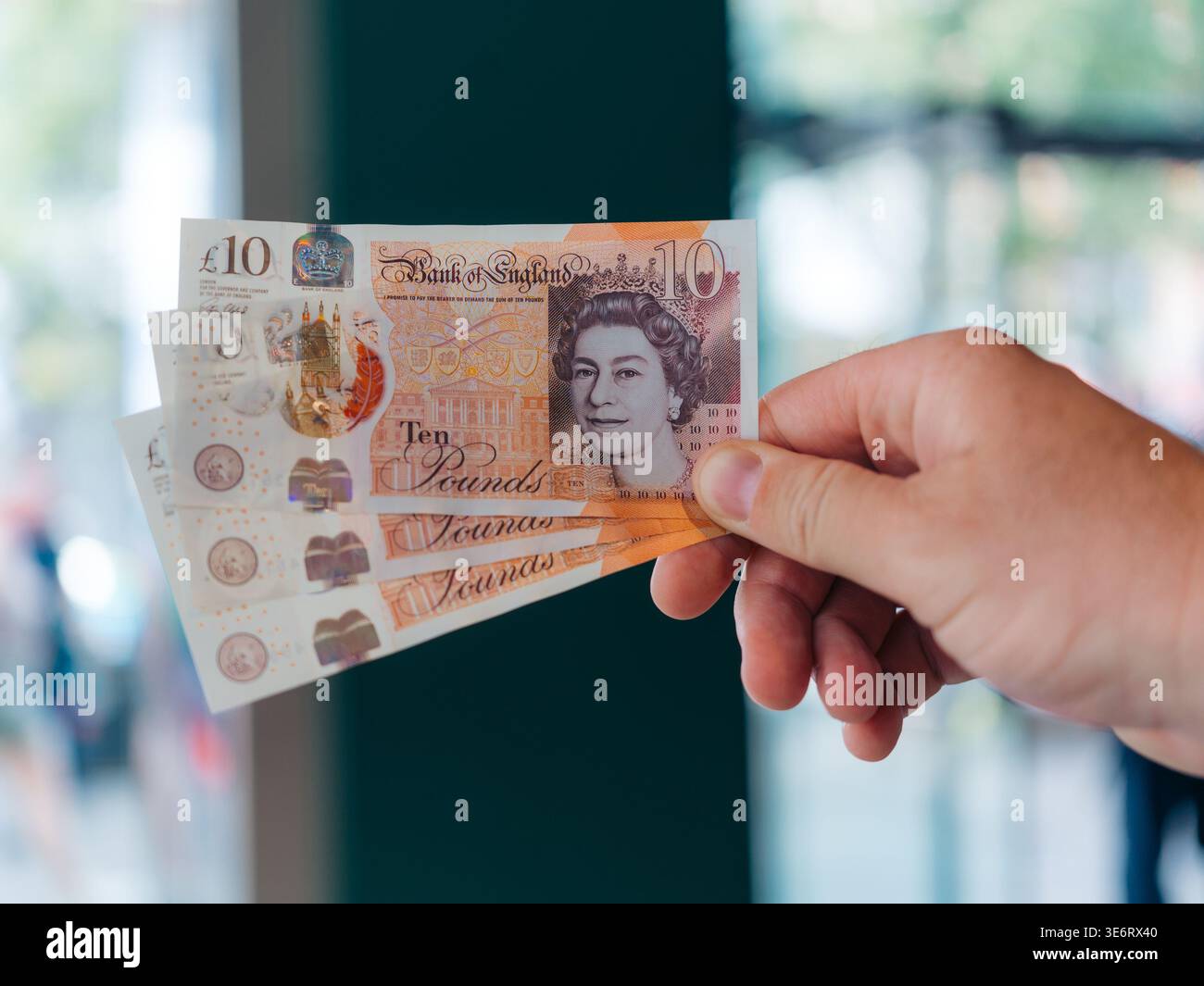 Londres, Royaume-Uni - 20 juin 2025 : vue d'une main tenant de nouvelles notes de dix livres, le papier net reflétant la lumière, un portrait de la reine Elizabeth Banque D'Images
