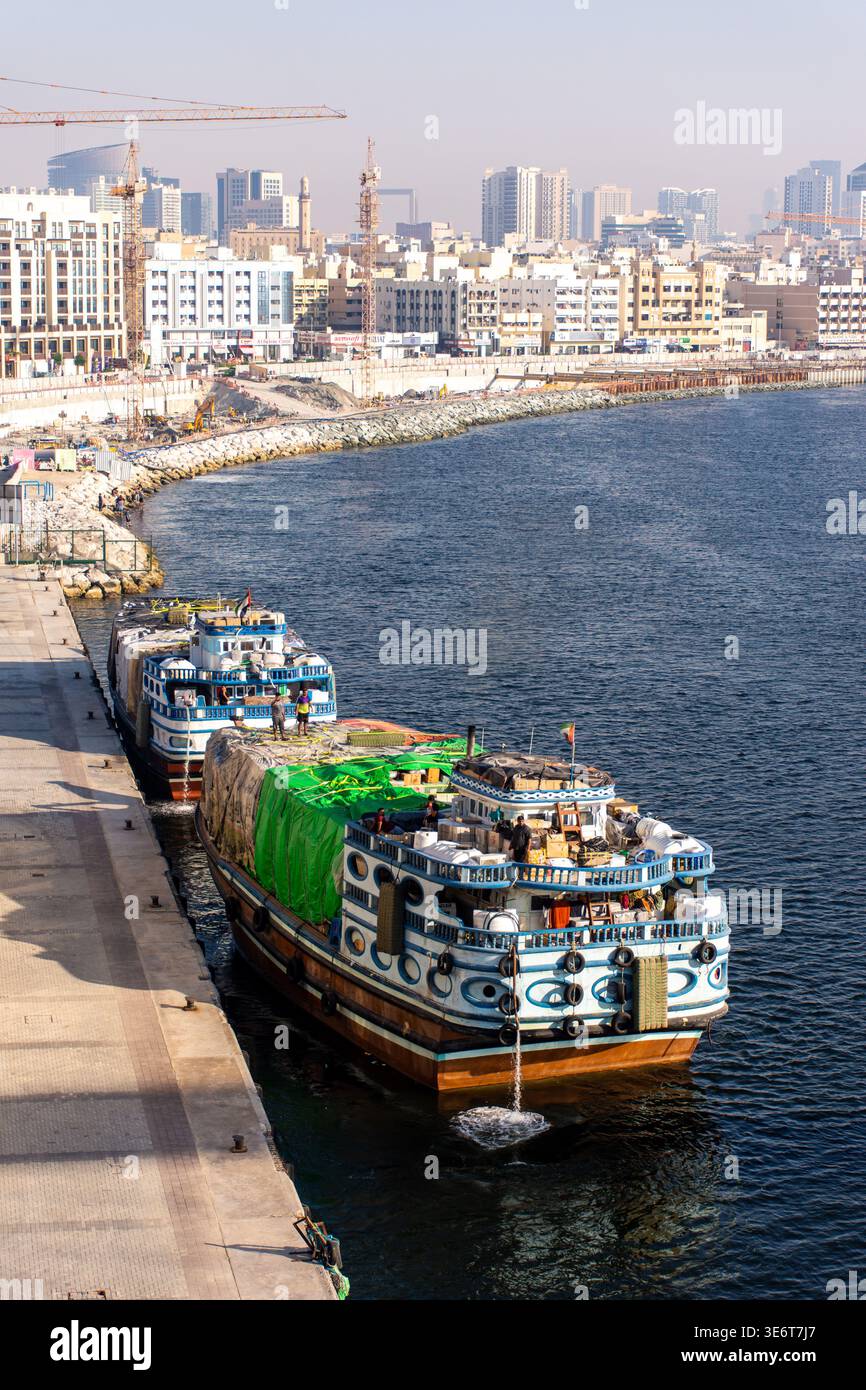 Bateaux à boutre traditionnels en bois chargés de cargaison recouverts de bâches vertes amarrés à un quai du port à Dubaï, Émirats arabes Unis. Banque D'Images