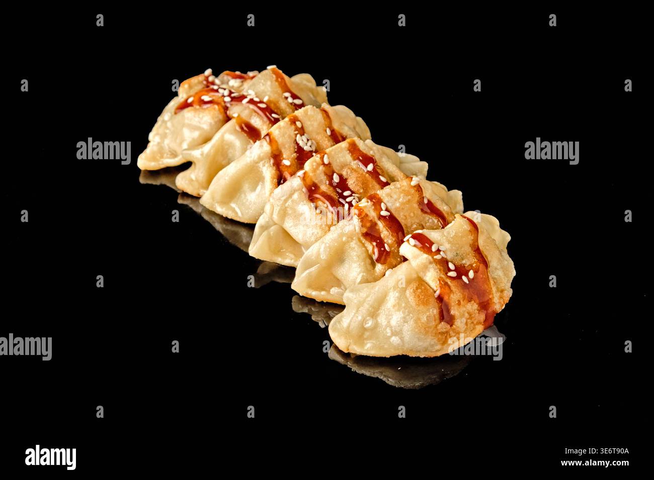 Rangée de boulettes poêlées avec croûte croustillante dorée isolée sur fond noir avec réflexion miroir. Concept de cuisine asiatique et d'Europe de l'est, s Banque D'Images