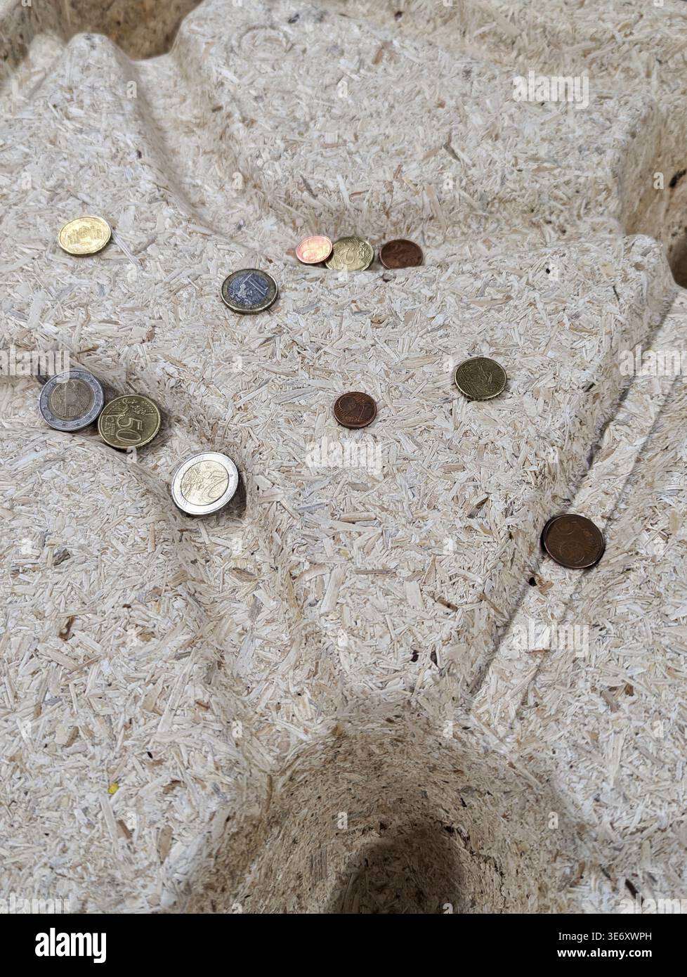 Pièces dispersées sur une alcôve en pierre altérée, petites niches encastrées contenant des devises usées assorties, lumière du jour douce créant des ombres douces, surf tactile rugueux Banque D'Images